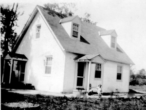 Elmington home with Celesta seated on the stoop and Jackie in the yard